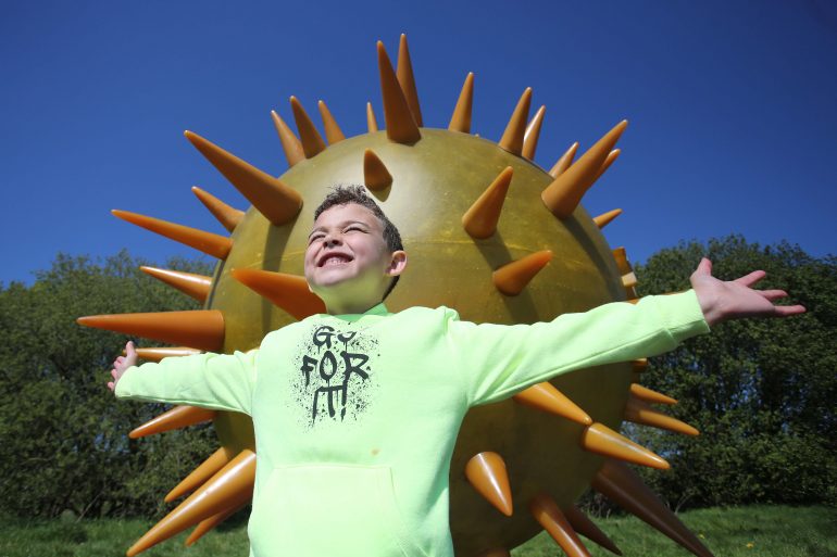 Boy posing in front of large artwork of the Sun