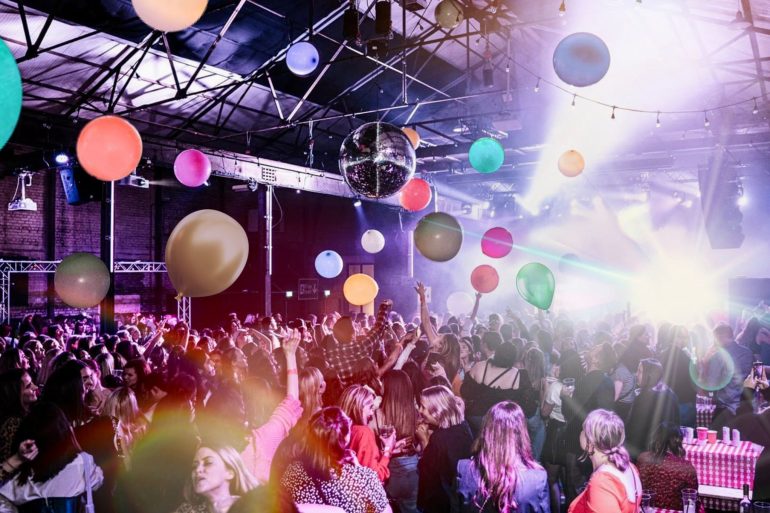 People on a dance floor at a nightclub with colourful balloons