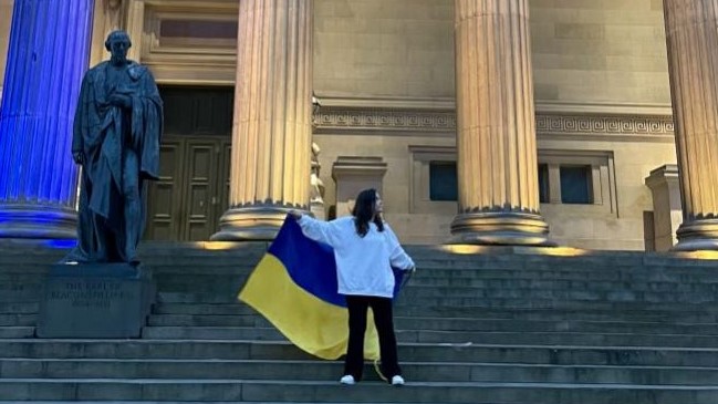 Veronika standing in front of St George's Hall holding an Ukraine flag