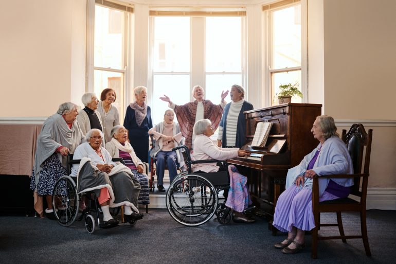 Care home residents singing around a piano
