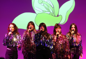 Welcome to Eurotopia singers facing forward holding microphones