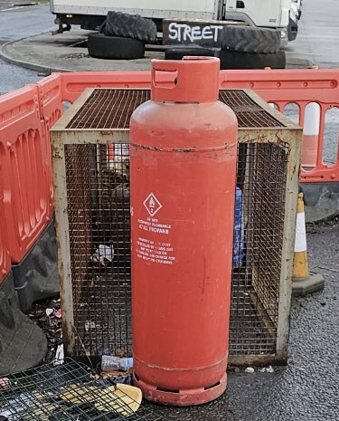 Industrial gas canister found within a pile of flytipped waste at an illegal bonfire site