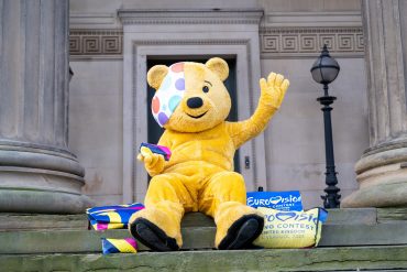 Pudsey sat on the steps of St George's Hall surrounded by Eurovision merchandise