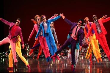 Dancers in colourful outfits on stage.