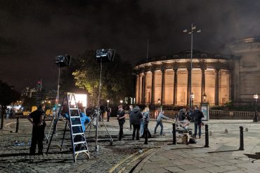Production crew filming on William Brown Street in the evening