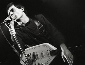 A man with a guitar singing in a microphone