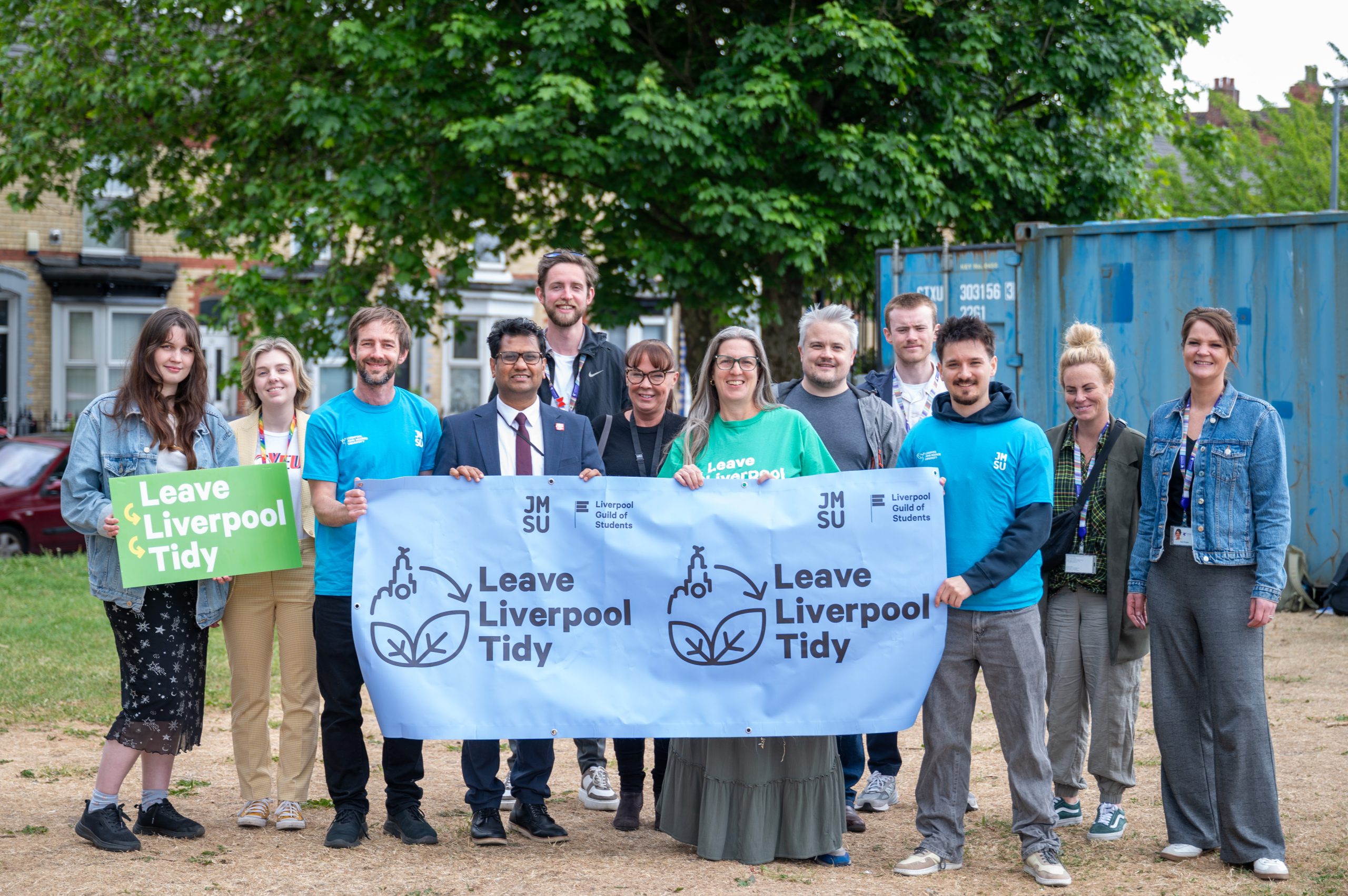 Members from the Guild of Students, Liverpool City Council, local Councillors and John Moores Students’ Union standing with a Leave Liverpool Tidy banner in front of a shipping container