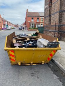 A skip on the road, filled with rubbish