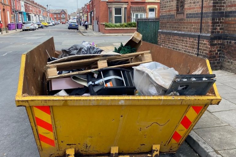 A skip on the road, filled with rubbish