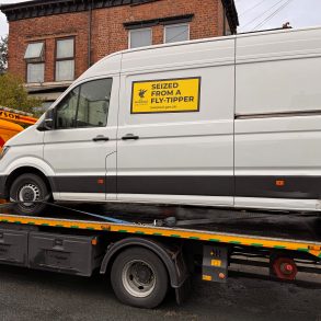 A van on the back of a pick-up, with 'seized from a fly-tipper' written on the side.