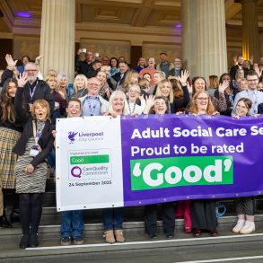 Adult Social Care Staff cheering holding holding banner which says 'Adult Social Care Services - Proud to be rate 'Good'. The sign is purple and the 'good' is in green.
