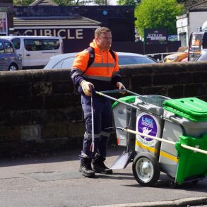 A person pushing a portable waste collection unit