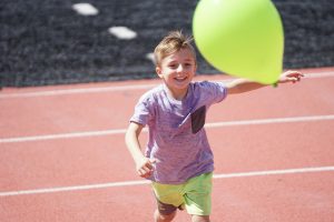 Child smiling running after a balloon