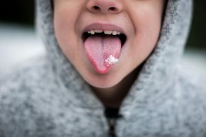 Child with their tongue out showing teeth.