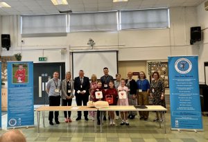 Group of adults and children at launch of defibrillator training