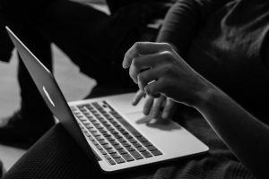 Black and white image of hands typing on laptop