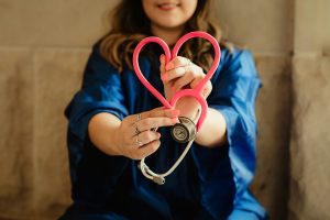 Female nurse holding a stethoscope in the shape of a heart.