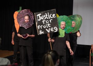 People dressed up as fruit and veg holding a sign saying Justice for fruit and veg