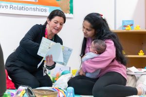 A staff member speaking to a mum holding her baby.