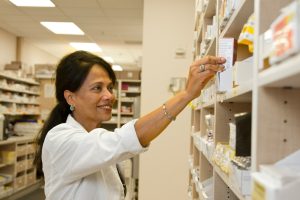 Staff picking a pill bottle off the shelf in a pharmacy